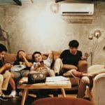 a group of friends sitting on the couch representing what moving in with friends looks like