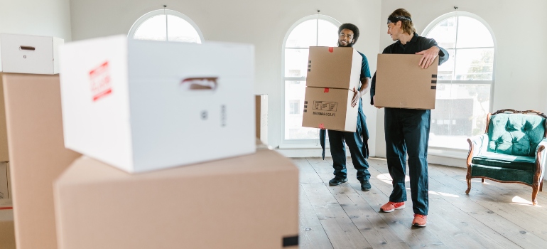 two guys carrying cardboard boxes