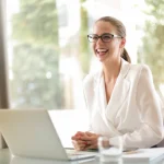 A smiling woman in front of her laptop