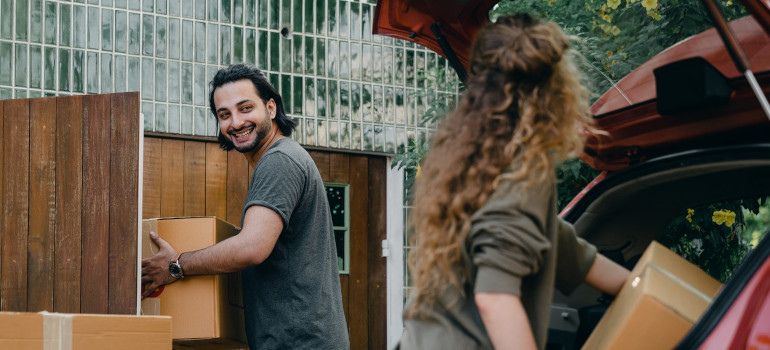 Happy couple unloading automobile while moving home