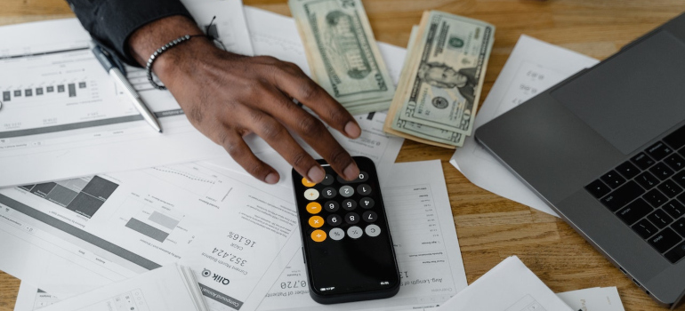 Desk with calculator, dollars, and papers.