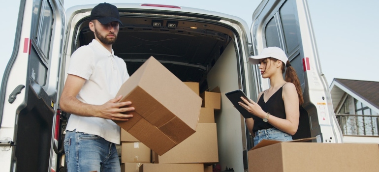 two movers Carson packing and checking boxes in from the van