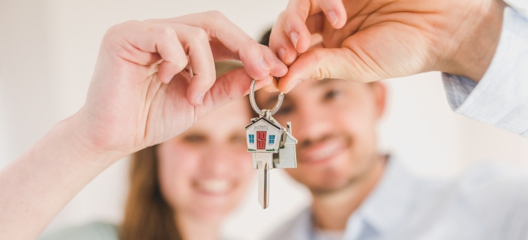 movers Carson will help a couple holding a key after buying a house