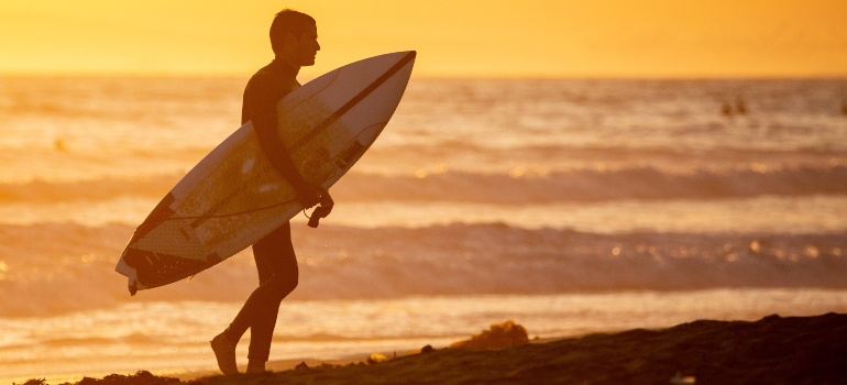 a surfer coming out of the water at sunset