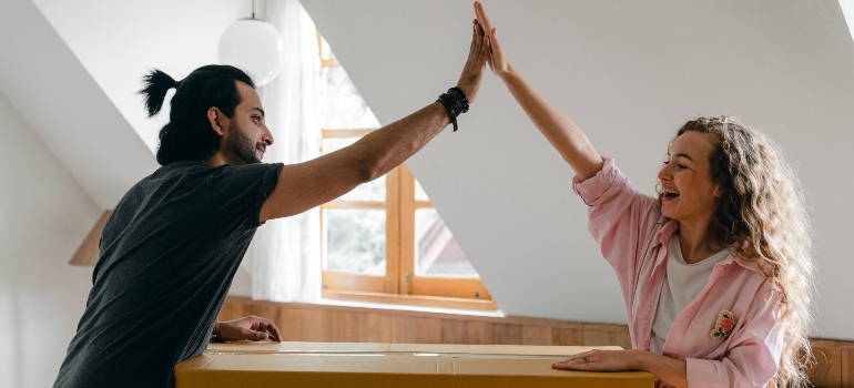 A man and a woman shaking hands to pack an essentials box when moving to San Clemente CA