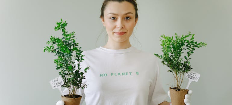 a girl holding two potted plants with some quotes on them implying environmental protection is important