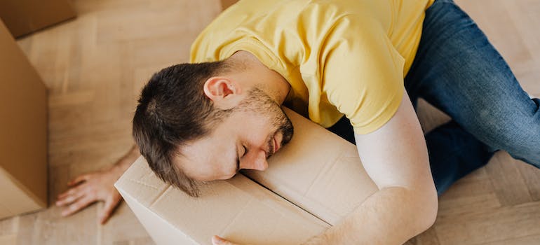 a man hugging a cardboard box while in emotional distress which is normal when you declutter your home before the move