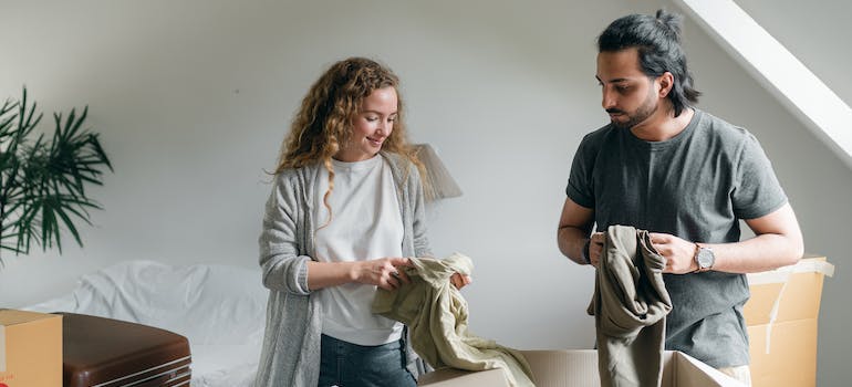 two people evaluating clothes before packing them in boxes which is a good strategy if you want to declutter before the move efficiently