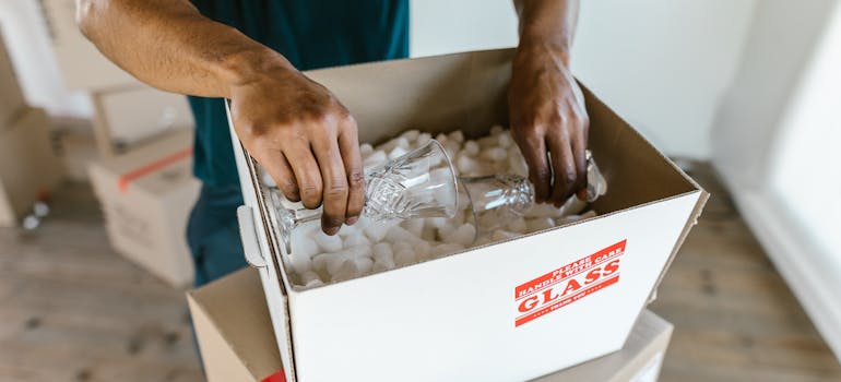 a man putting crystal glasses into a box marked to contain glass