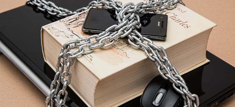 laptop, phone, and a book tied in a bundle with a chain