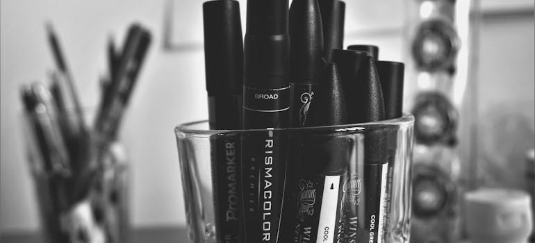 Black markers in a glass